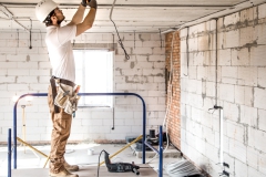 electrician-installer-with-tool-his-hands-working-with-cable-construction-site